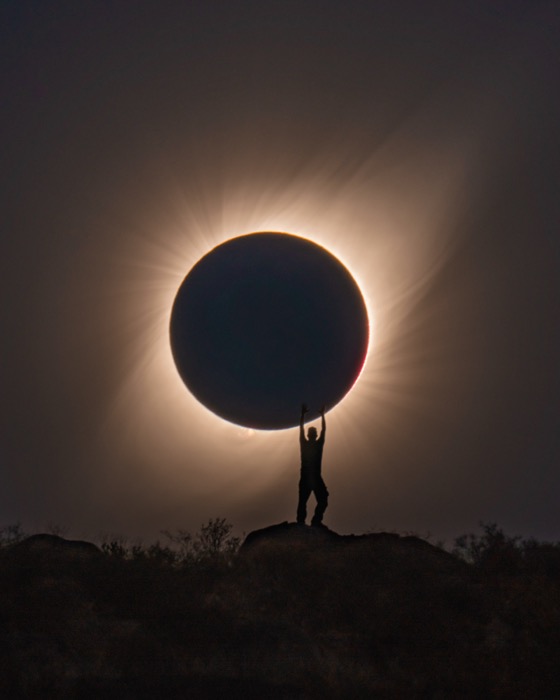 Silhouette holding the eclipsed sun