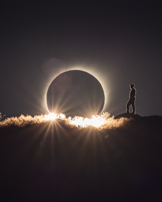 The eclipsed sun behind a ridge